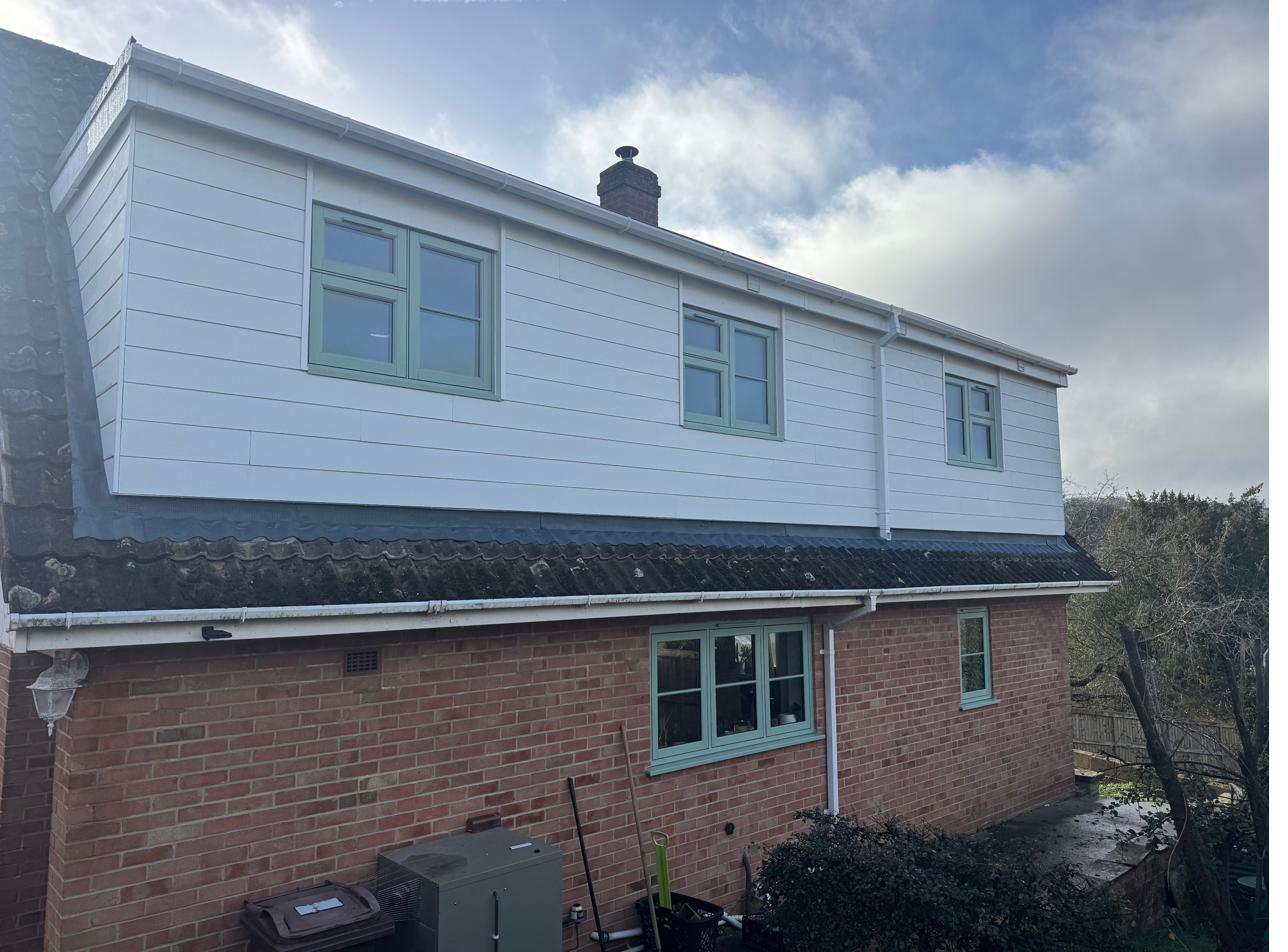 Rear dormer loft conversion completed by Next Level Lofts in Gloucestershire, white cladding with sage green windows